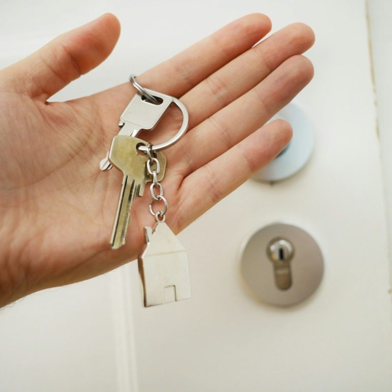 24/7 Notdienst Schlüsseldienst aus Schwetzingen bei Türöffnung Eine Hand hält Schlüssel, darunter ein kleiner Schlüsselanhänger in Form eines Hauses.